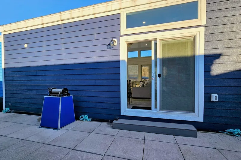 Slide: The Image of Modern 2025 houseboat with blue exterior and sliding glass door. - 2