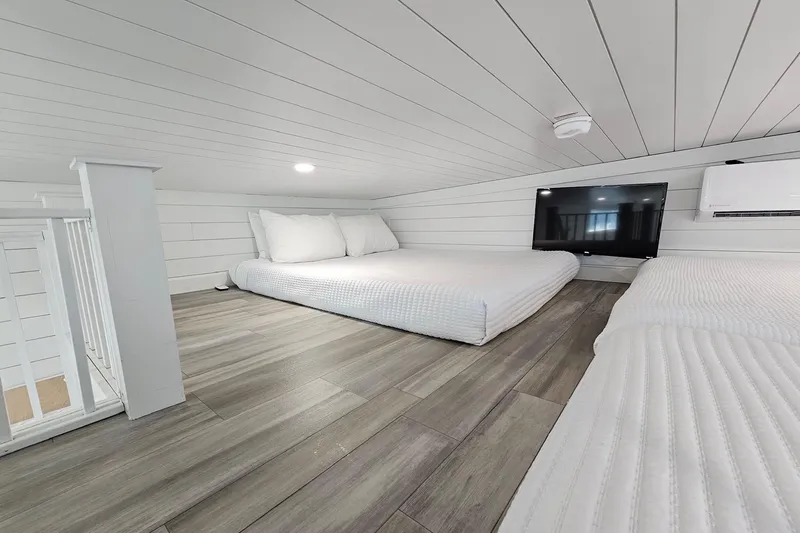 Slide: The Image of Modern 2025 houseboat loft with beds, TV, and sleek wood flooring. - 21