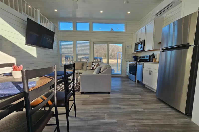 Slide: The Image of Modern 2025 houseboat interior with kitchen, dining area, and large windows overlooking water. - 6