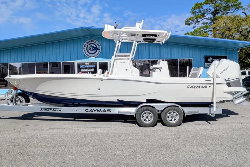 The Image of 2026 Caymas 281 HB boat on trailer outside a blue marina building. - 0