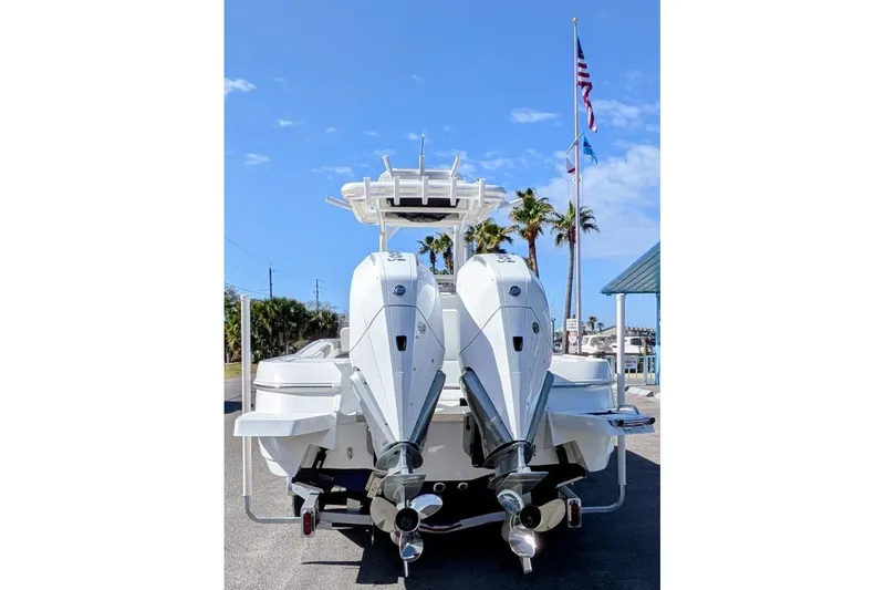 Slide: The Image of 2026 Caymas 281 HB boat on trailer, parked outside marina with flags and blue sky. - 2