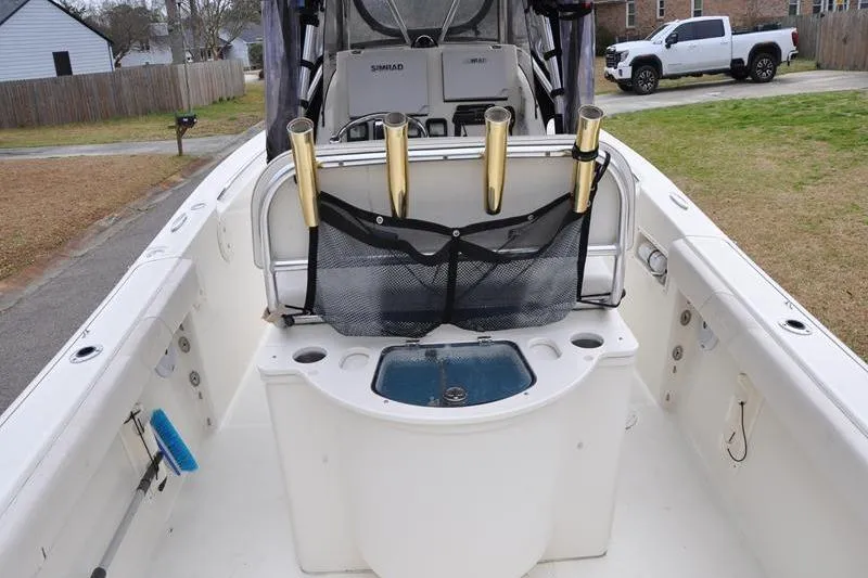 Slide: The Image of 2006 Pursuit 2570 Center Console boat with rod holders and livewell, parked in a driveway. - 29