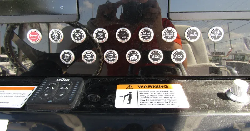 Slide: The Image of Control panel of a 2024 Wellcraft 263 Fisherman boat with various buttons and warning labels. - 18