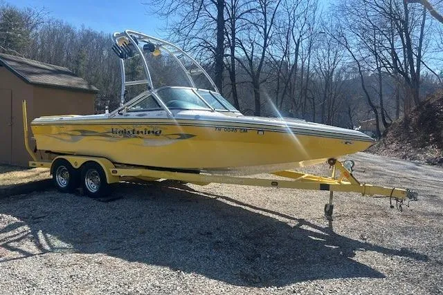 The Image of Yellow 2004 Centurion Lightning boat on trailer, parked outdoors. - 1