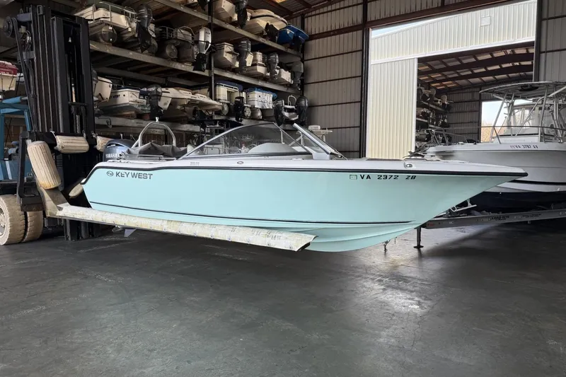 The Image of 2024 Key West 203 DFS boat in storage, lifted by a forklift in a warehouse. - 0