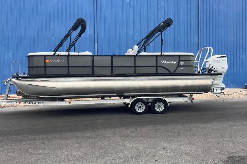 Slide: The Image of 2023 Bentley Pontoons 243 Navigator on trailer, parked by blue wall. - 1