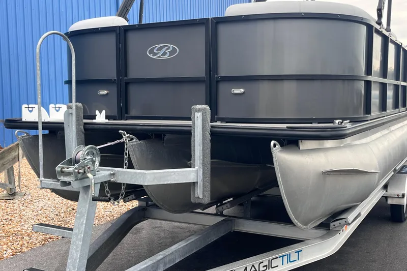 Slide: The Image of 2023 Bentley Pontoons 243 Navigator on trailer, sleek design, blue building background. - 4