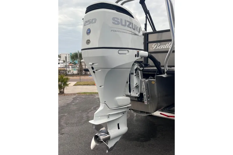 Slide: The Image of 2023 Bentley Pontoons 243 Navigator with Suzuki outboard motor, parked outdoors. - 8