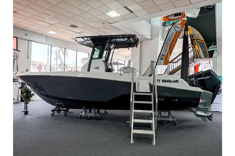 Slide: The Image of 2024 Wellcraft 263 Fisherman boat displayed indoors with ladder and Mercury engine. - 2