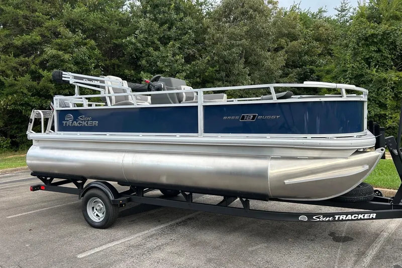 Slide: The Image of 2026 Sun Tracker Bass Buggy 18 DLX pontoon boat on trailer, parked outdoors. - 4