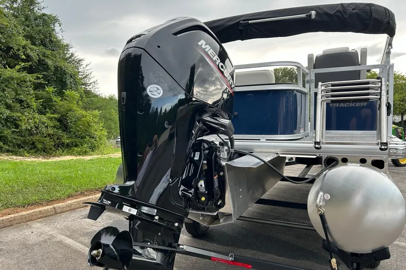 Slide: The Image of 2026 Sun Tracker Bass Buggy 18 DLX with Mercury outboard motor, parked outdoors. - 6