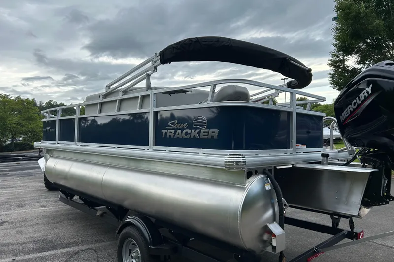 Slide: The Image of 2026 Sun Tracker Bass Buggy 18 DLX pontoon boat with Mercury engine, parked outdoors. - 1