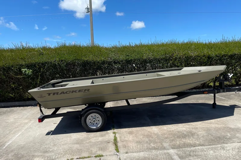 The Image of 2026 Tracker Grizzly 1648 Utility boat on trailer, parked outdoors under blue sky. - 0