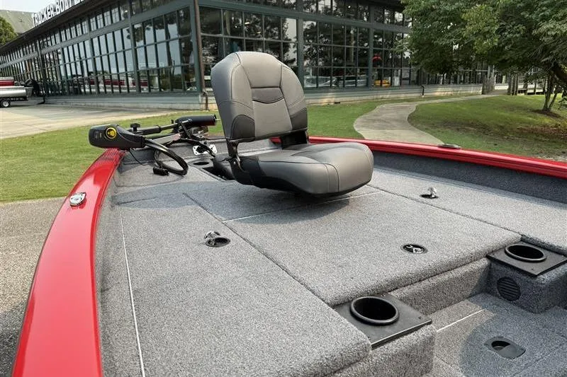 Slide: The Image of 2026 Tracker Pro Team 175 boat with gray seating and red trim, parked near a modern building. - 5