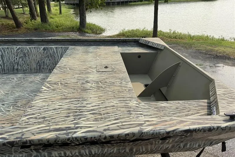 Slide: The Image of 2026 Tracker Grizzly 1648 Utility boat with camouflage design near a serene lake. - 14