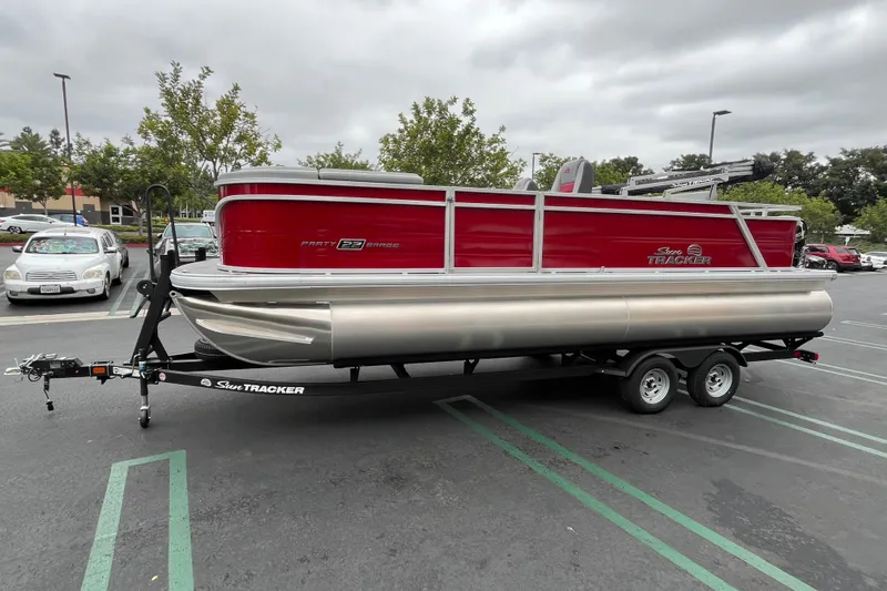 Slide: The Image of 2026 Sun Tracker Party Barge 22 RF DLX pontoon boat on trailer in parking lot. - 1