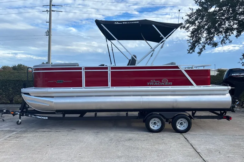 The Image of 2026 Sun Tracker Party Barge 22 RF DLX pontoon boat on trailer, red and silver design. - 0