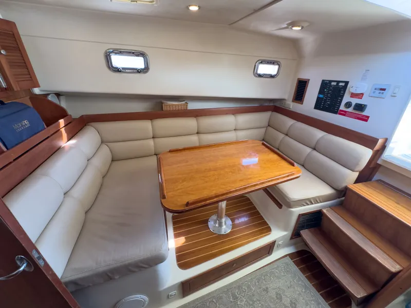 Slide: The Image of Interior of a 2004 Mainship Pilot 34 yacht with wooden table and cushioned seating. - 30