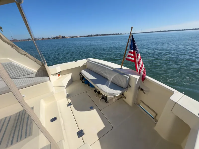 Slide: The Image of 2004 Mainship Pilot 34 boat with American flag on calm water. - 6
