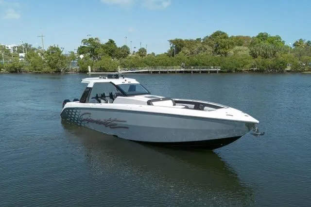 Slide: The Image of 2025 Cigarette 42' Auroris boat on calm water, surrounded by lush greenery. - 10