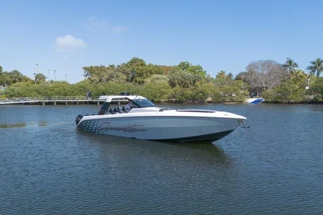 Slide: The Image of 2025 Cigarette 42' Auroris boat cruising on a calm lake with lush greenery. - 7