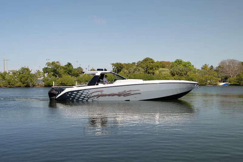 Slide: The Image of 2025 Cigarette 42' Auroris boat cruising on a calm lake with lush greenery. - 8