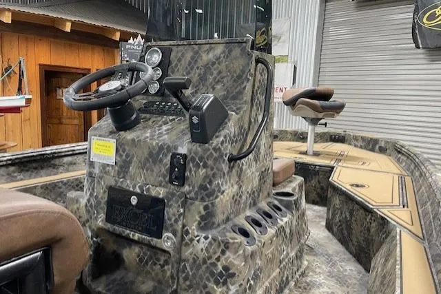 Slide: The Image of 2026 Excel 203 Bay Pro Elite boat interior with camouflage design and steering console. - 3
