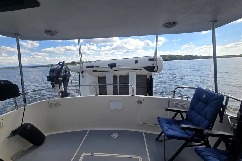 Slide: The Image of Nordic Tug 42 Flybridge 2000, rear deck view with seating, overlooking serene water and sky. - 11