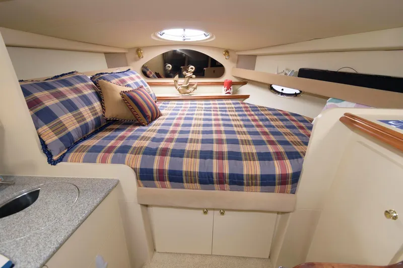 Slide: The Image of 2002 Cruisers Yachts 3275 Express cabin with plaid bedding and cozy interior. - 12