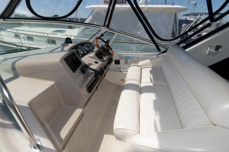 Slide: The Image of 2002 Cruisers Yachts 3275 Express cockpit with white leather seating and helm station. - 4