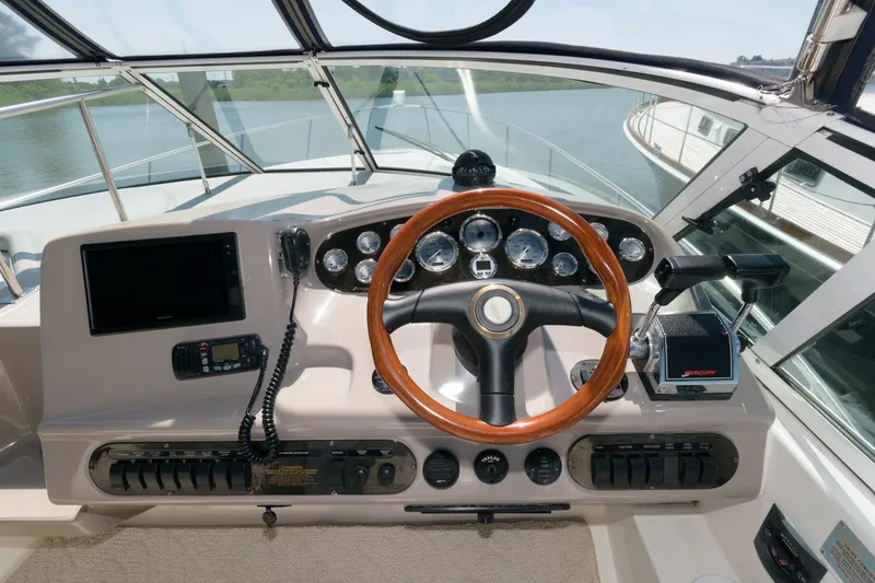 Slide: The Image of 2002 Cruisers Yachts 3275 Express helm with wooden steering wheel and modern controls. - 5