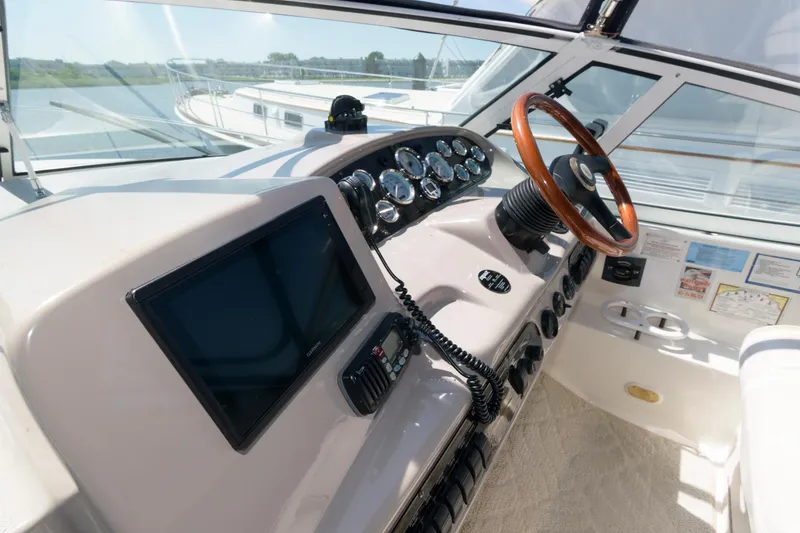 Slide: The Image of 2002 Cruisers Yachts 3275 Express helm with modern navigation equipment and wooden steering wheel. - 6