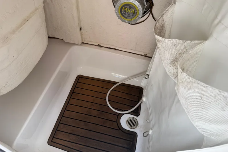 Slide: The Image of 2021 Tidewater 232 CC Adventure boat interior with wooden floor mat and shower area. - 15