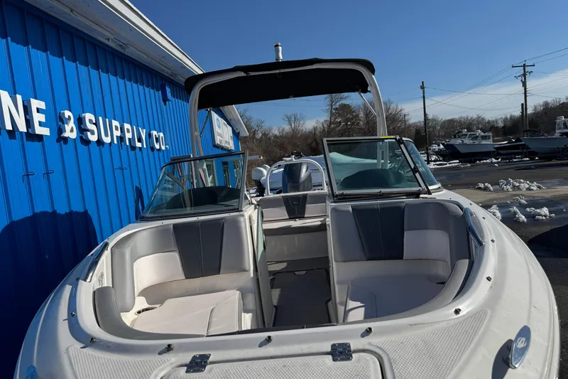 Slide: The Image of 2019 Chaparral 21 H2O Sport OB boat with open bow seating, docked near blue building. - 17