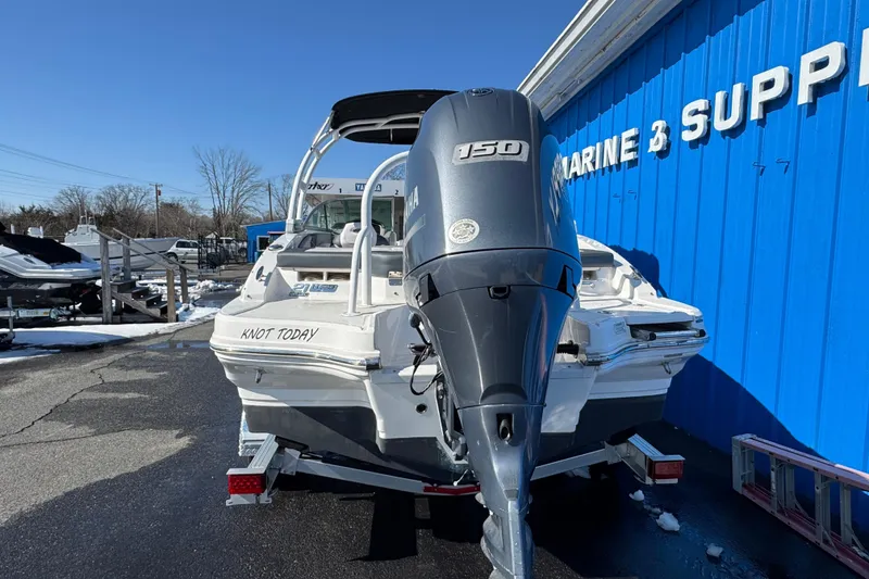 Slide: The Image of 2019 Chaparral 21 H2O Sport OB boat with Yamaha engine, parked near blue building. - 2