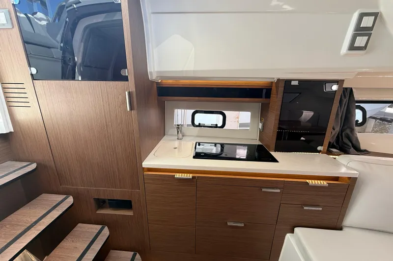 Slide: The Image of 2022 Jeanneau Leader 10.5 WA Series 2 interior kitchen with modern wood cabinetry and compact design. - 18