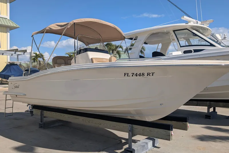 Slide: The Image of 2019 Scout 215 XSF boat with canopy, docked under clear blue sky. - 2