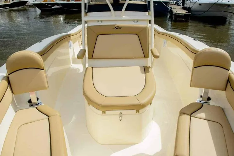 Slide: The Image of 2019 Scout 215 XSF boat interior with tan seating, docked on calm water. - 35