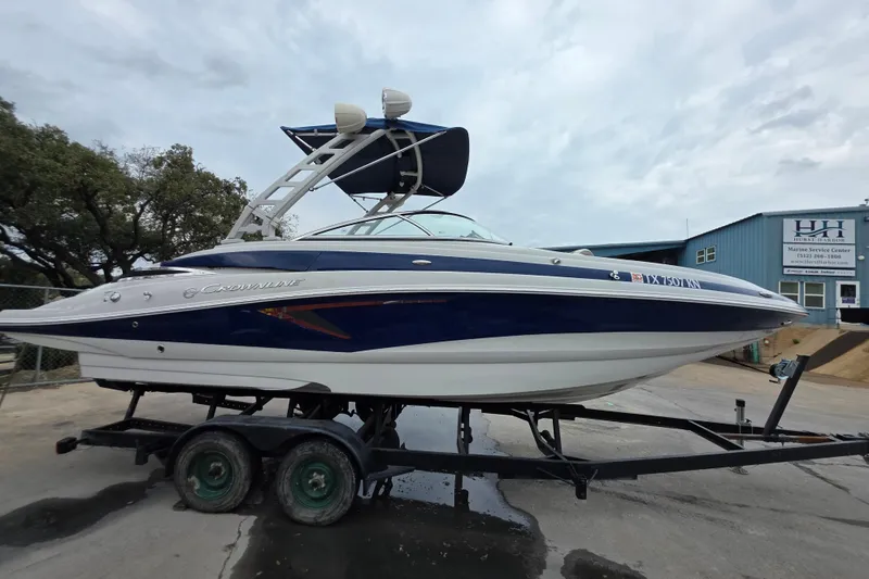 Slide: The Image of 2022 Crownline Eclipse E255 boat on trailer, parked outdoors near a marine service center. - 63