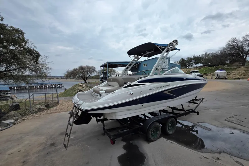 Slide: The Image of 2022 Crownline Eclipse E255 boat on trailer by lakeside, overcast sky. - 64