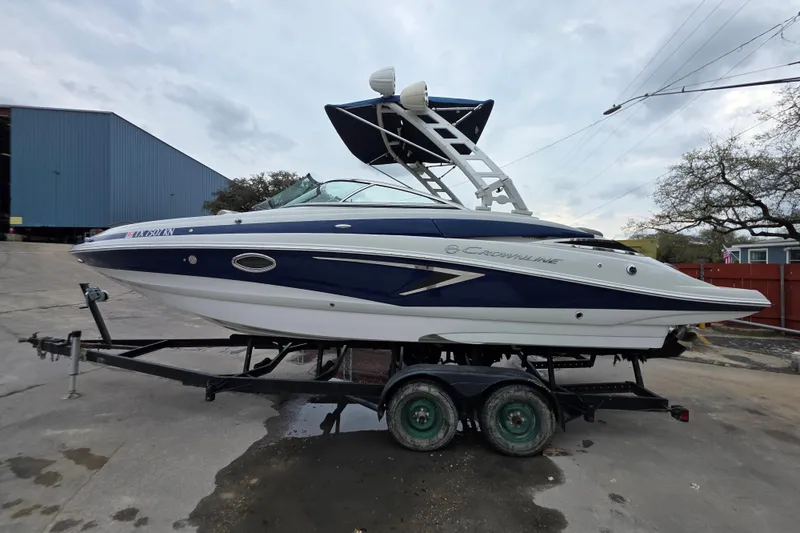 Slide: The Image of 2022 Crownline Eclipse E255 boat on trailer, blue and white design, parked outdoors. - 68