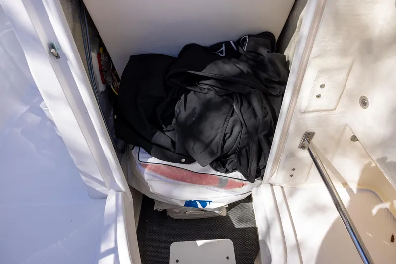 Slide: The Image of 2020 Robalo R202 Explorer storage compartment with clothes and equipment. - 12