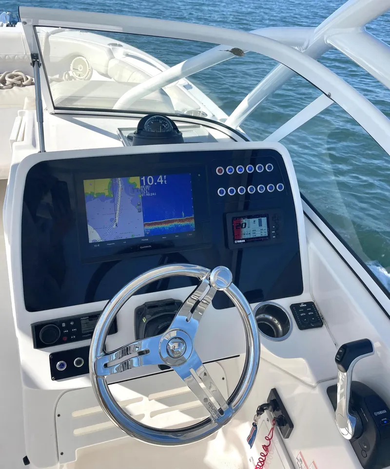 Slide: The Image of 2020 Edgewater 348 CX boat dashboard with steering wheel and navigation display on open water. - 12