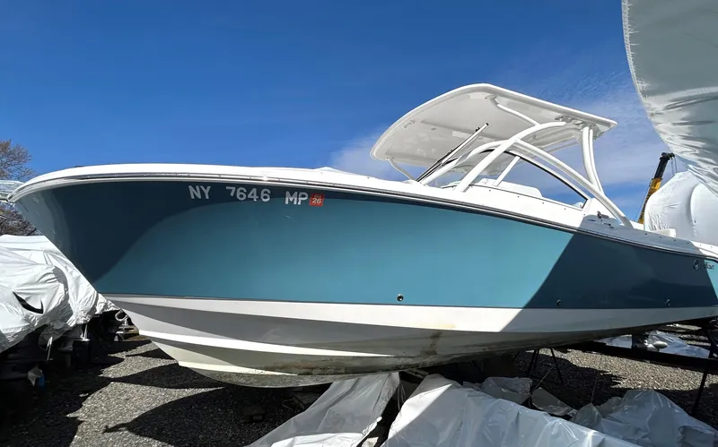 Slide: The Image of 2020 Edgewater 348 CX boat with blue hull, docked on land under clear sky. - 5