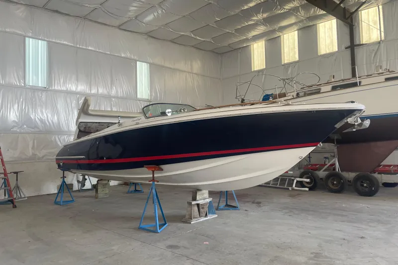 Slide: The Image of 2006 Chris-Craft Corsair 28 boat in indoor storage, elevated on stands. - 2