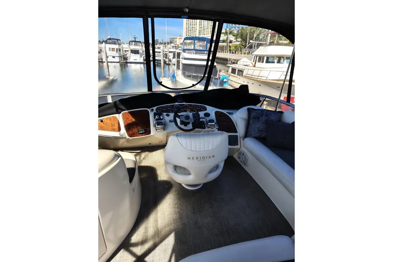 Slide: The Image of 2006 Meridian 459 Motoryacht helm with marina view, featuring luxurious seating and controls. - 14