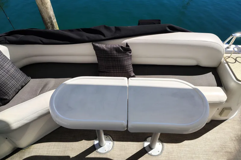 Slide: The Image of 2006 Meridian 459 Motoryacht seating area with table and cushions, docked by blue water. - 18