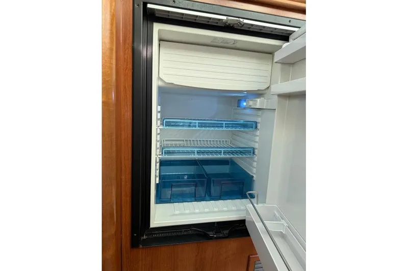 Slide: The Image of Open refrigerator in a 2013 Gemini Legacy 35, featuring blue storage bins and shelves. - 10