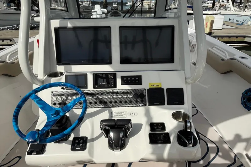 Slide: The Image of 2022 Tidewater 292 CC Adventure boat dashboard with dual screens and blue steering wheel. - 15