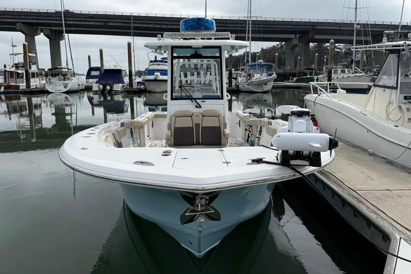 Slide: The Image of 2022 Tidewater 292 CC Adventure boat docked in a marina, surrounded by other vessels. - 4